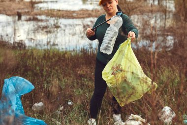 Gönüllü ve çevreci eylemci çöplerle dolu kirli göl kıyılarını temizliyor..
