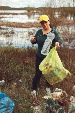 Gönüllü ve çevreci eylemci çöplerle dolu kirli göl kıyılarını temizliyor..