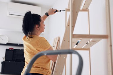 Yeni ahşap raf ve mobilyaları bir araya getiren kadın..