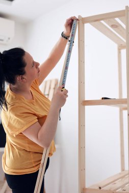 Yeni ahşap raf ve mobilyaları bir araya getiren kadın..