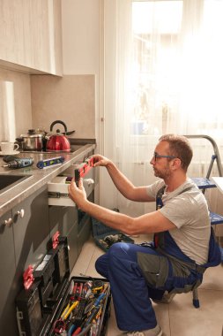 Tamirci dairedeki mutfak dolaplarını tamir ediyor..