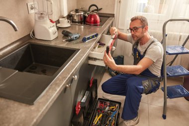 Tamirci dairedeki mutfak dolaplarını tamir ediyor..