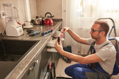 Tamirci dairedeki mutfak dolaplarını tamir ediyor..