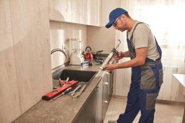 Tamirci dairedeki mutfak dolaplarını tamir ediyor..