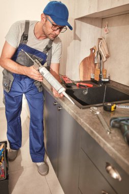 Tamirci dairedeki mutfak dolaplarını tamir ediyor..