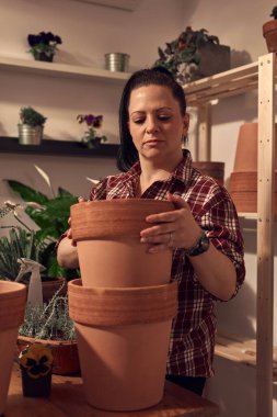 Kapalı alandaki çiçeklerle ilgilenen bir kadın..
