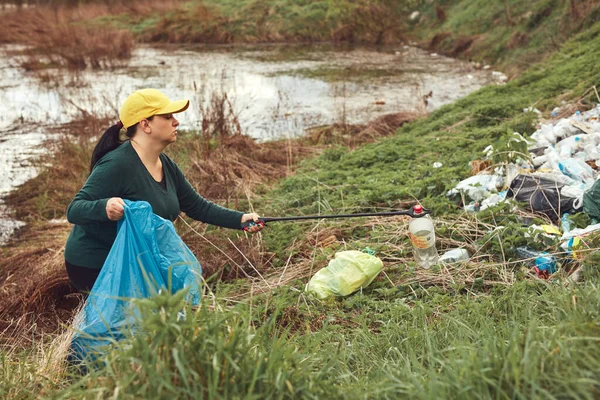 stock image Volunteer and environmental activist cleaning dirty lake shore filled with trash.