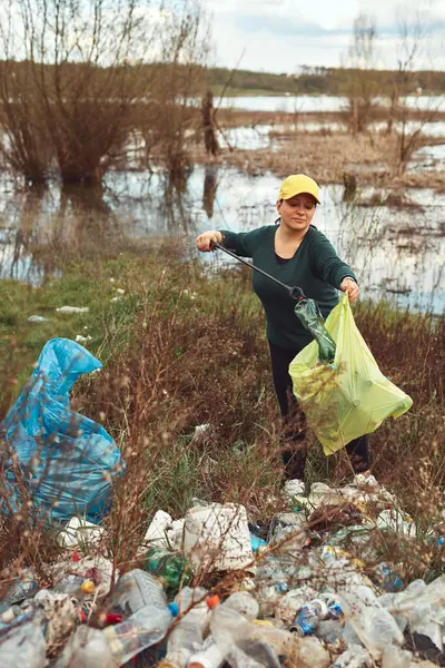 stock image Volunteer and environmental activist cleaning dirty lake shore filled with trash.