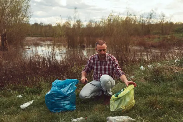 stock image Volunteer and environmental activist cleaning dirty lake shore filled with trash.