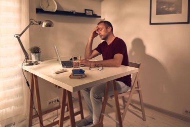 Evde dizüstü bilgisayarla çalışmaktan yorgun düşmüş bir adam..