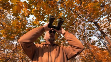 Kuşları ve diğer hayvanları dürbünle gözlemleyen amatör kuş gözlemcisi..