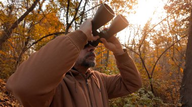 Kuşları ve diğer hayvanları dürbünle gözlemleyen amatör kuş gözlemcisi..