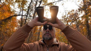 Kuşları ve diğer hayvanları dürbünle gözlemleyen amatör kuş gözlemcisi..