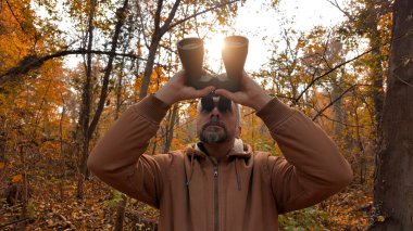 Kuşları ve diğer hayvanları dürbünle gözlemleyen amatör kuş gözlemcisi..