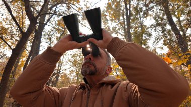 Amateur birdwatcher observing birds and other animals in nature with binoculars. clipart