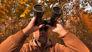 Kuşları ve diğer hayvanları dürbünle gözlemleyen amatör kuş gözlemcisi..
