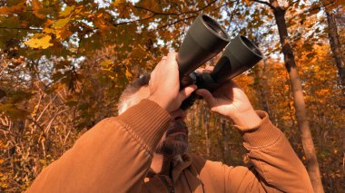 Kuşları ve diğer hayvanları dürbünle gözlemleyen amatör kuş gözlemcisi..