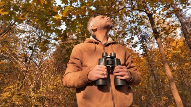 Kuşları ve diğer hayvanları dürbünle gözlemleyen amatör kuş gözlemcisi..