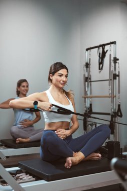 Young women exercising in a gym on pilates machines.