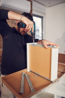 Yeni bir dairede çalışan ve mobilya montajlayan bir adam..