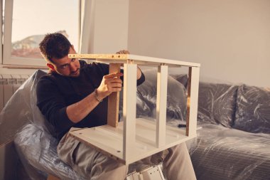 Yeni bir dairede çalışan ve mobilya montajlayan bir adam..