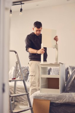 Yeni bir dairede çalışan ve mobilya montajlayan bir adam..