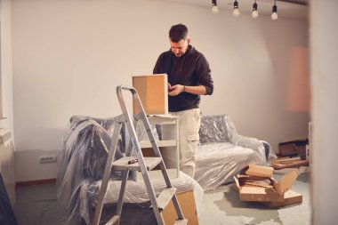 Yeni bir dairede çalışan ve mobilya montajlayan bir adam..