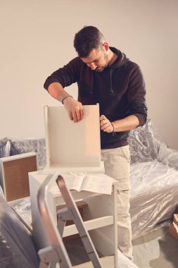 Yeni bir dairede çalışan ve mobilya montajlayan bir adam..
