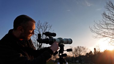 Güneş tutulmasını ve Güneş 'i teleskop ve özel güneş filtresiyle gözlemleyen amatör astronom..