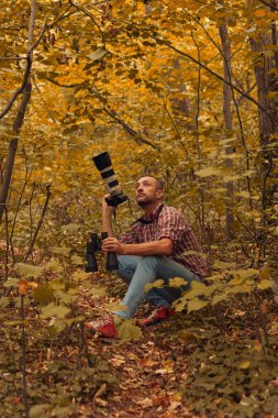 Dürbün ve kamera kullanan adam doğada kuşları ve hayvanları izliyor..