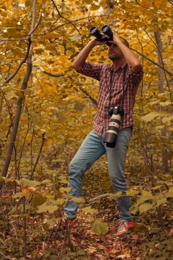 Dürbün ve kamera kullanan adam doğada kuşları ve hayvanları izliyor..