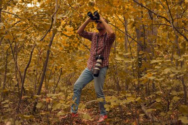 Dürbün ve kamera kullanan adam doğada kuşları ve hayvanları izliyor..