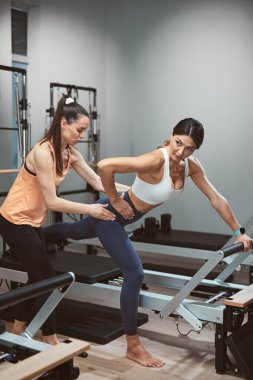 Young women exercising in a gym on pilates machines.