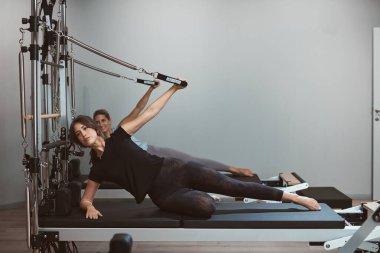 Young women exercising in a gym on pilates machines.