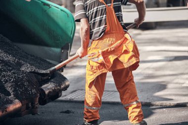 İnşaat işçileri kamu caddesinde yeni bir asfalt tabakası üzerinde çalışıyorlar..