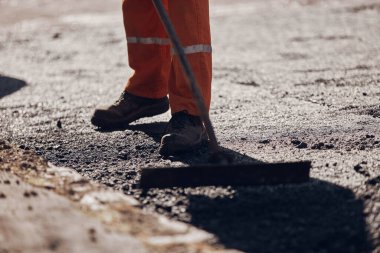 İnşaat işçileri kamu caddesinde yeni bir asfalt tabakası üzerinde çalışıyorlar..