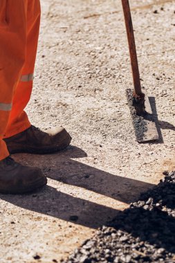İnşaat işçileri kamu caddesinde yeni bir asfalt tabakası üzerinde çalışıyorlar..