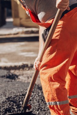 İnşaat işçileri kamu caddesinde yeni bir asfalt tabakası üzerinde çalışıyorlar..