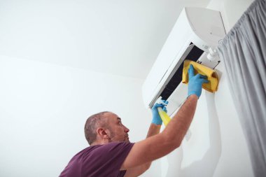 Evdeki havalandırmayı temizleyen ve koruyan adam..