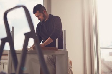 Yeni bir dairede çalışan ve mobilya montajlayan bir adam..