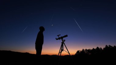 Amatör astronom akşam gökyüzüne bakıyor, gezegenleri, yıldızları, ayı ve teleskopla diğer gök cisimlerini gözlemliyor..