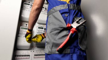 Technician working on a modern electricity power meter station in a building. clipart