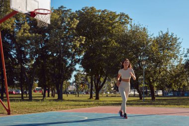 Genç bir kadın güneşli yaz gününde şehir parkında egzersizden sonra dinleniyor ve zıplıyor..