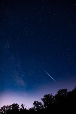 Meteor yağmuru izleri ve kırsal siluetleri olan Samanyolu yıldızları.