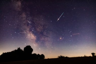 Milky Way stars with meteor shower trails and countryside silhouettes. clipart