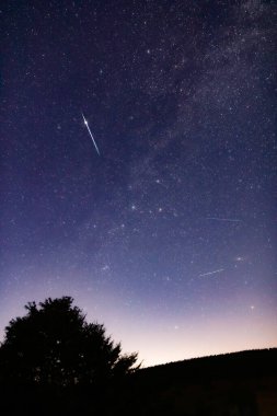 Meteor yağmuru izleri ve kırsal siluetleri olan Samanyolu yıldızları.