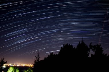 Meteor yağmuru izleri ve kırsal siluetleri olan Samanyolu yıldızları.
