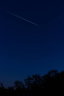 Meteor yağmuru izleri ve kırsal siluetleri olan Samanyolu yıldızları.