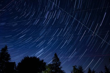 Meteor yağmuru izleri ve kırsal siluetleri olan Samanyolu yıldızları.