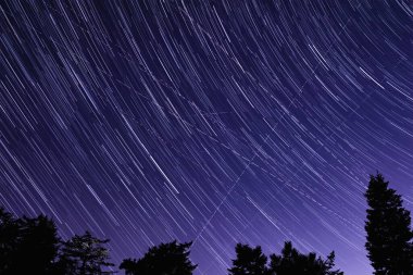 Meteor yağmuru izleri ve kırsal siluetleri olan Samanyolu yıldızları.